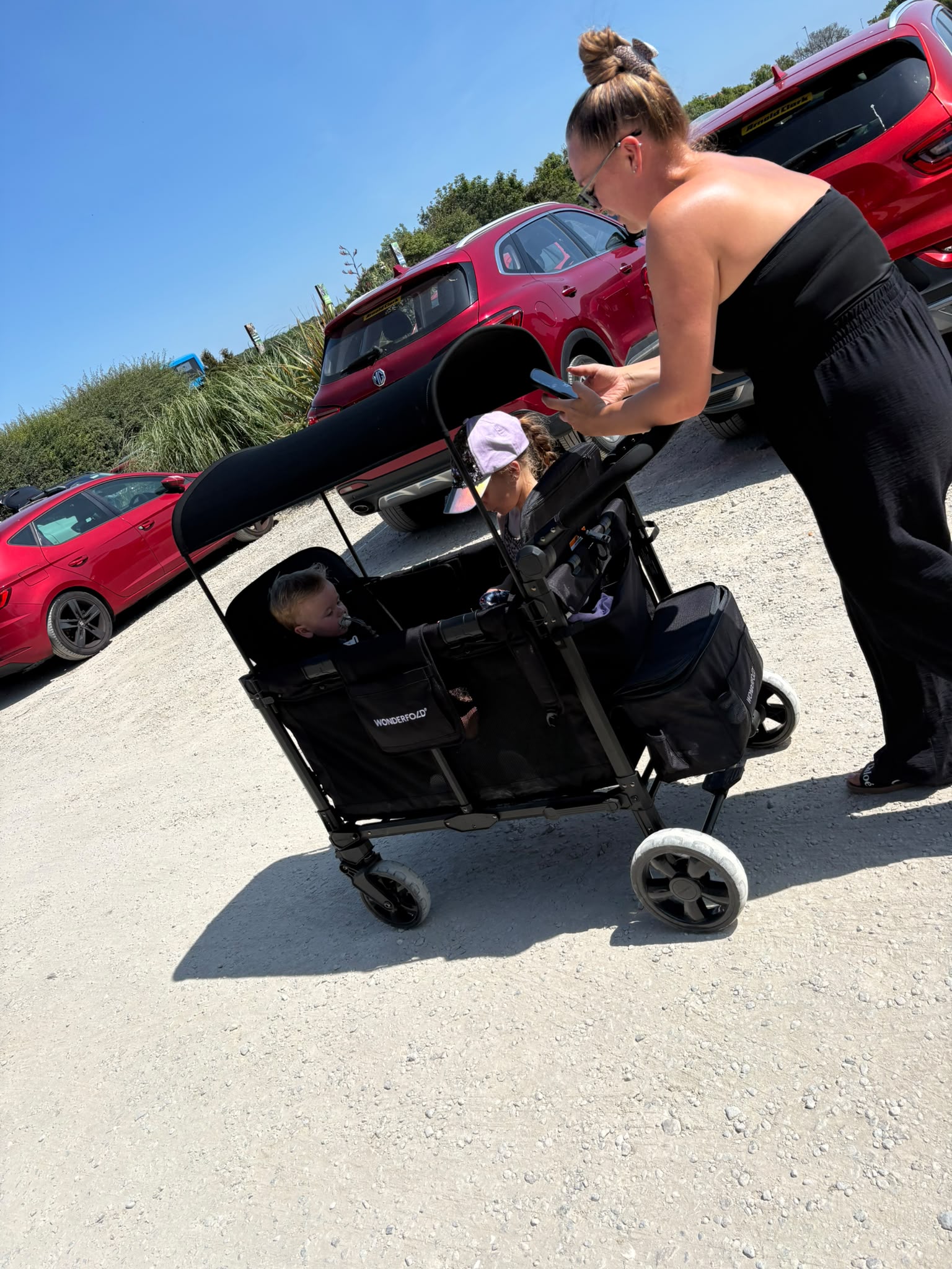 Mother pushing two children in the WonderFold wagon on a sunny day out