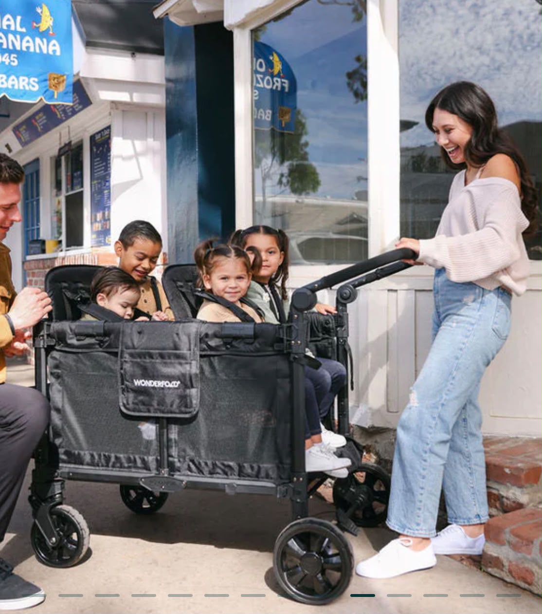 Cheerful family with four children outside a building with the WonderFold wagon