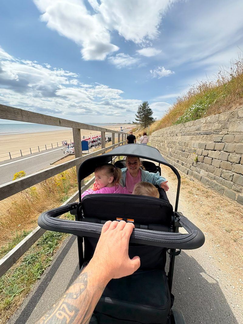 Family pushing the WonderFold wagon along the seafront promenade
