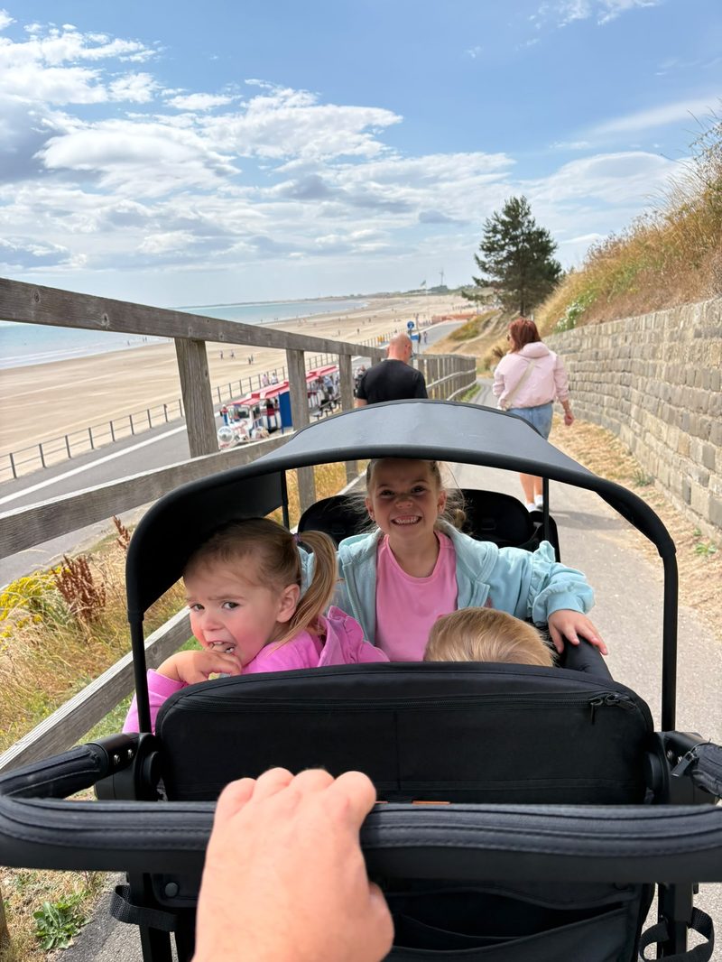 Children smiling in the WonderFold wagon by the beach